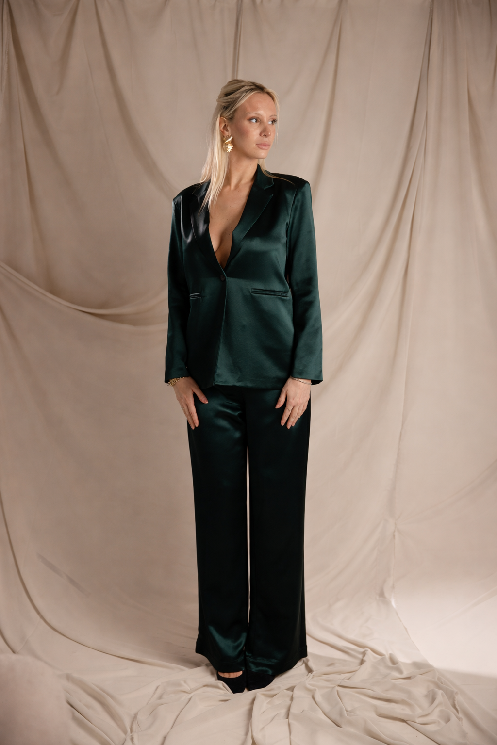 Woman wearing a green satin suit against a beige backdrop
