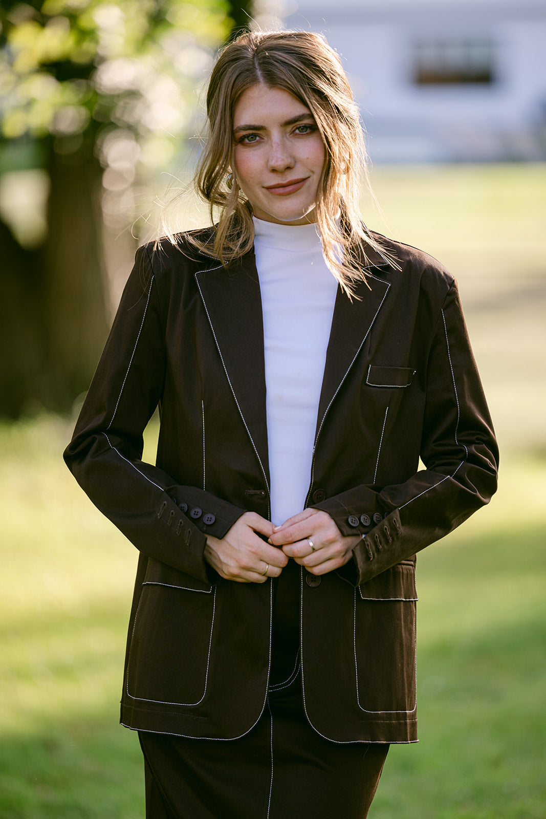 Woman wearing a brown stitch blazer over a white shirt outdoors
