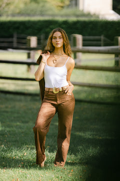 woman wearing brown suede trousers with a white tak