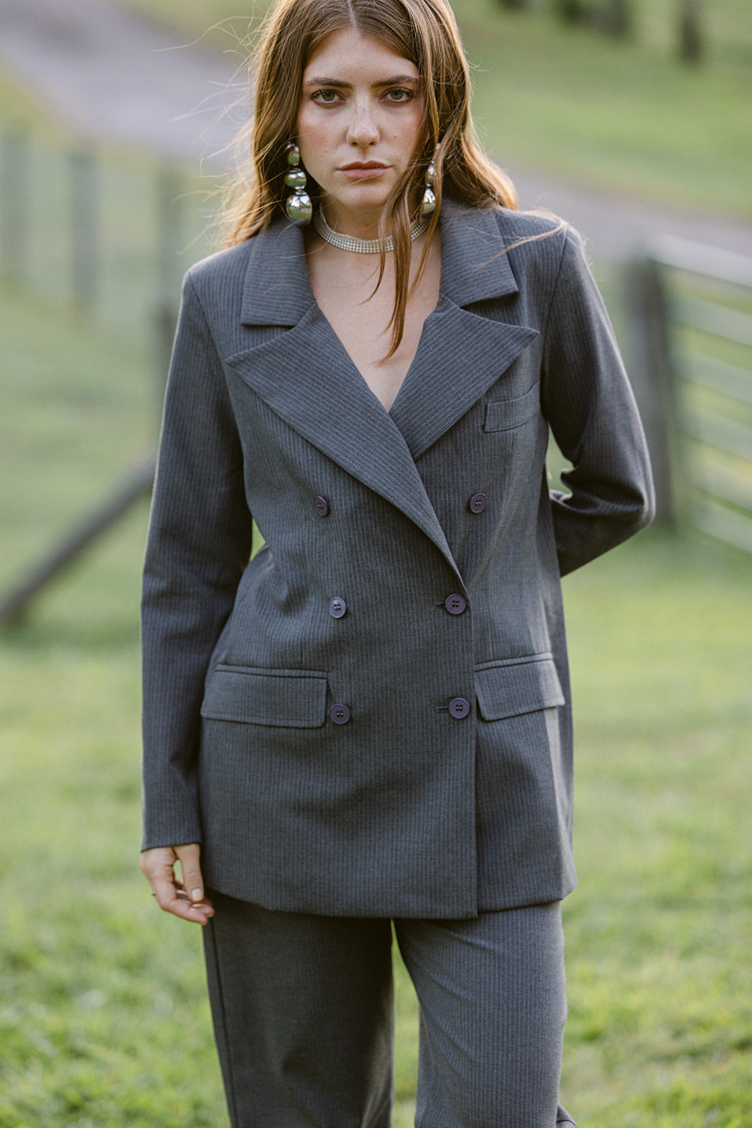 woman wearing a grey pinstripe double breasted blazer with matching pants